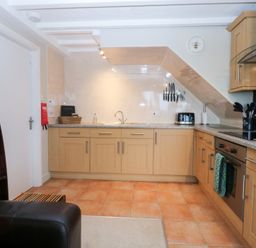 A kitchen with cabinetry, sink, and stove at Oak Cottage Dinas Dinlle near Caernarfon