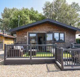 A wooden cabin with a black railing deck and outdoor furniture at Oakwood 2 @ Pinewood Retreat in Pinewood
