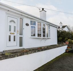 The exterior of a white house with a white door and windows neudd wen red wharf bay near benllech