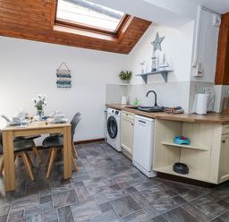 A kitchen with a dining table and appliances at Saddlers Cottage in Weymouth