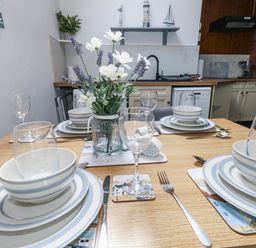 A dining table set with plates and glasses at Saddlers Cottage in Weymouth
