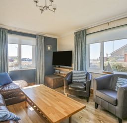 A living room with leather chairs a wooden coffee table and a wall-mounted television at Seaspray in St Bees