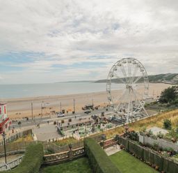 A beach with a Ferris wheel playground and a red and white building near the shore at The Seahome in Scarborough
