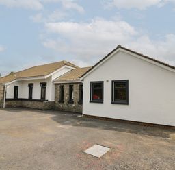 A single story house with white and stone walls and a tiled roof on a paved area at Heritage in St Clears