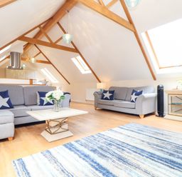 A living room with two grey sofas a coffee table and a blue striped rug at Potters Barn Trevarno near Helston