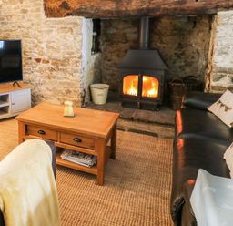 A living room with a fireplace a wooden coffee table a flat screen tv and leather sofas at The Bake House in Bettws