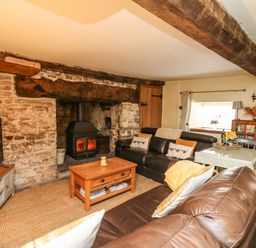 A living room with a wood burning stove wooden coffee table and leather sofas at The Bake House in Bettws