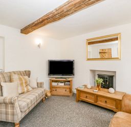 A living room with a plaid sofa a television on a wooden stand a wood stove and a wooden coffee table at 4 Wallflower Row Mordiford near Hereford