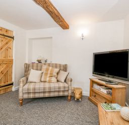 A living room with a plaid sofa and television on wooden furniture at 4 Wallflower Row Mordiford near Hereford