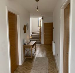 A hallway with wooden doors a wooden console table mirrors and stairs at Galwad y Mor in Broad Haven