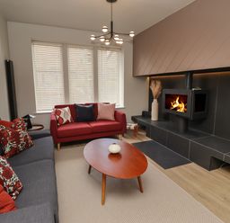 A living room with a gray sofa a red sofa a wooden coffee table and a fireplace at Glencoe House in Wooler