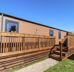 Exterior view of a wooden lodge with a deck and stairs leading up at Mayflower Lodge in Runswick Bay near Staithes