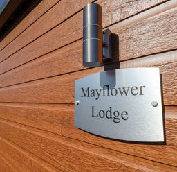 A metal sign reading Mayflower Lodge on a wooden exterior wall near a black window frame at Mayflower Lodge in Runswick Bay near Staithes