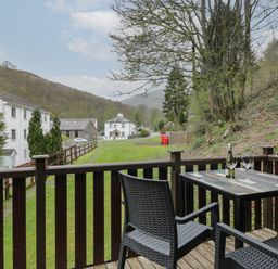 A balcony with a table and two chairs overlooking greenery and houses at Canadian Cabin 37 in Keswick