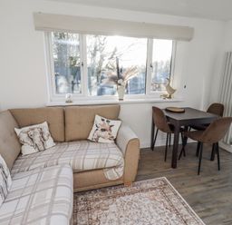 A living room with a sofa and dining area at Old Colliery Cottage in Shilbottle