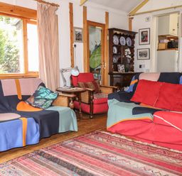 A living room with sofas and cushions a wooden cabinet with plates and framed pictures on walls at Can Yr Afon in Beddgelert