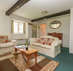 A living room with sofas coffee table and a cabinet at Thatch Cottage in Buckland Newton