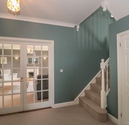 A hallway with turquoise walls carpeted stairs and glass paneled double doors leading to a living room at Cherry Tree House in Highbridge