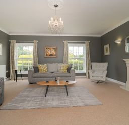 A living room with gray sofas a fireplace and a chandelier at Cherry Tree House in Highbridge
