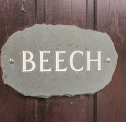 A stone plaque with BEECH engraved on it mounted on a wooden surface at Beech Timber Lodge in Keswick