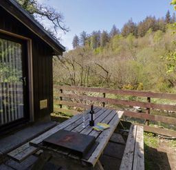 An outdoor seating area with a table and wine bottle at Beech Timber Lodge in Keswick