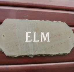 A stone plaque with the word ELM mounted on a wooden wall at Elm Lodge in Keswick