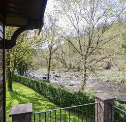 A view of a river and trees from a balcony at Elm Lodge in Keswick