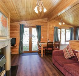 A living room with a sofa and dining table at Elm Lodge in Keswick