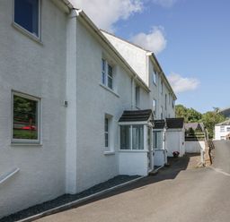 A driveway next to a white building with windows and small porch entrances at Garden Cottage No 1 in Keswick