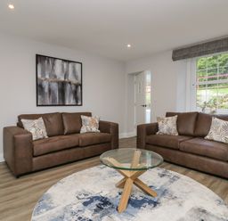 A living room with two brown sofas a round glass coffee table and a circular rug at Garden Cottage No 1 in Keswick