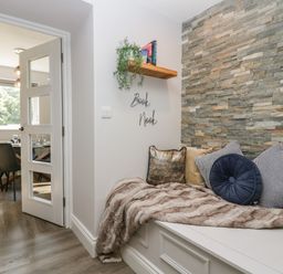 A book nook with cushions and a throw beside a door leading to a dining room at Garden Cottage No 1 in Keswick