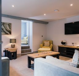 A living room with a sofa coffee table armchair and television at Greta House in Keswick