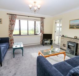 A living room with two blue sofas two coffee tables a TV and a fireplace at Pinegarth in Catton near Allendale