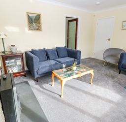 A living room with blue sofas a coffee table and a bookshelf at Pinegarth Catton near Allendale