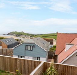 Houses with fenced yards near a beach with a grassy hill in the background at 11 Ebbtide in Porth