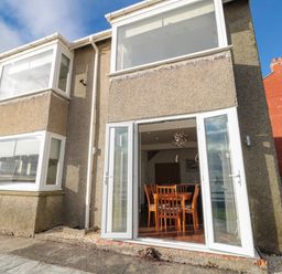 Back exterior of a house with open glass doors leading to a dining area at Fairwinds in Newbiggin-By-The-Sea