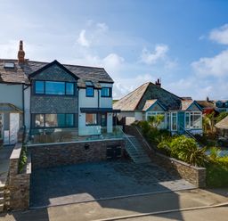 A residential street with two houses one with a modern extension and a paved driveway at 12 Tintagel Terrace in Port Isaac