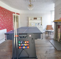 A room with a pool table, a small round table with a chair, a fireplace, and a white cabinet at Braeside Lyme Regis
