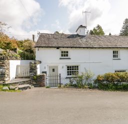 A white stone cottage with slate roof and small garden at Old Farm Cottage in Skelwith Fold