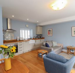 A kitchen and living area with wooden floor and blue walls at Lark Rise in Alnmouth
