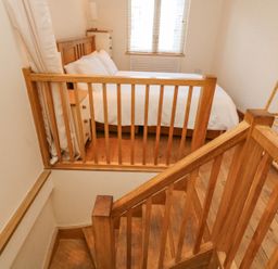 A bedroom with a bed bedside tables and a wooden clothes rack at The Loft Cottage in Totnes