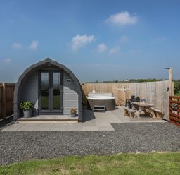 A small pod with double doors a hot tub and outdoor seating area at Nebo Pod in Amlwch