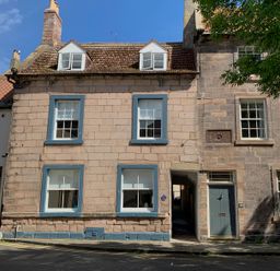 Exterior of a stone house with blue window frames and a green door beside an alleyway at The Indigo House in Berwick-Upon-Tweed