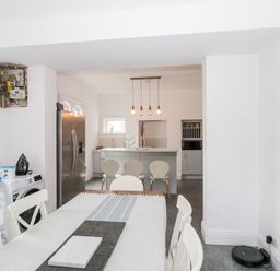 A dining area with a table and chairs leading to a kitchen with an island and bar stools at Castle Manor in Scarborough