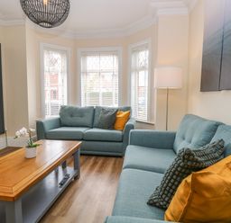 A living room with two blue sofas pillows wooden coffee table and floor lamp at Seaside House in Gorleston-On-Sea
