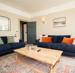 A living room with two blue sofas a wooden coffee table a patterned rug and wall art at Haulfryn in Barmouth