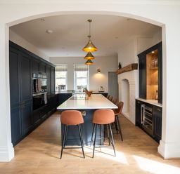 A kitchen with a large island and bar stools under pendant lights at Haulfryn in Barmouth