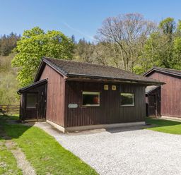 A cabin surrounded by trees and a gravel pathway at Chestnut Timber Lodge in Keswick