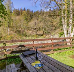 An outdoor table with a wine bottle and glasses at Chestnut Timber Lodge in Keswick