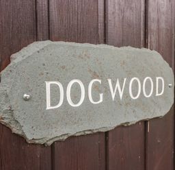 A carved stone sign with the word dog wood mounted on a wooden surface at Dogwood Timber Lodge in Keswick